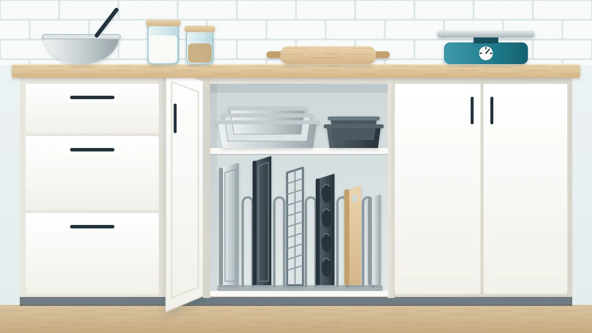 Narrow lower cabinet with its door open, baking sheets, a cooling rack and a muffin tin standing on edge between dividers, cake pans nested above