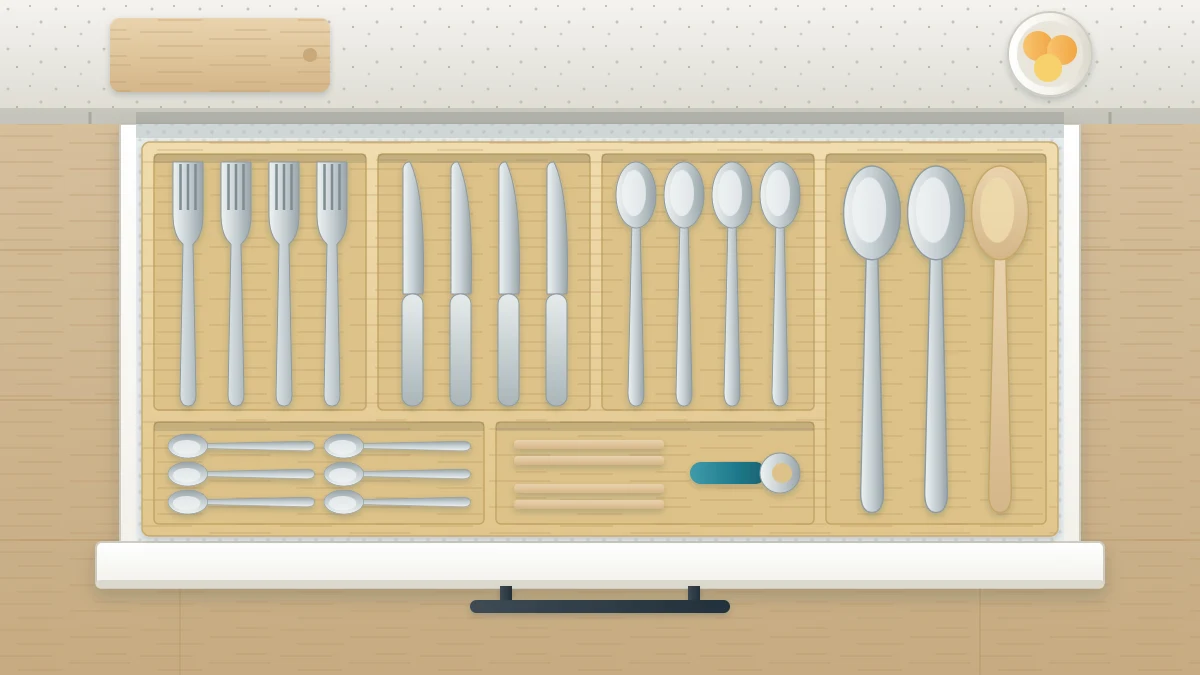 A wide open kitchen drawer seen from above with a bamboo tray holding forks, knives, spoons and serving spoons in separate lanes